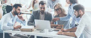 People around a desk looking at a laptop