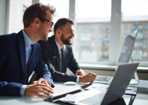 Two men at a desk working on their computers