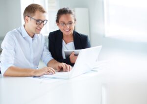 Man and woman at a desk looking at a laptop